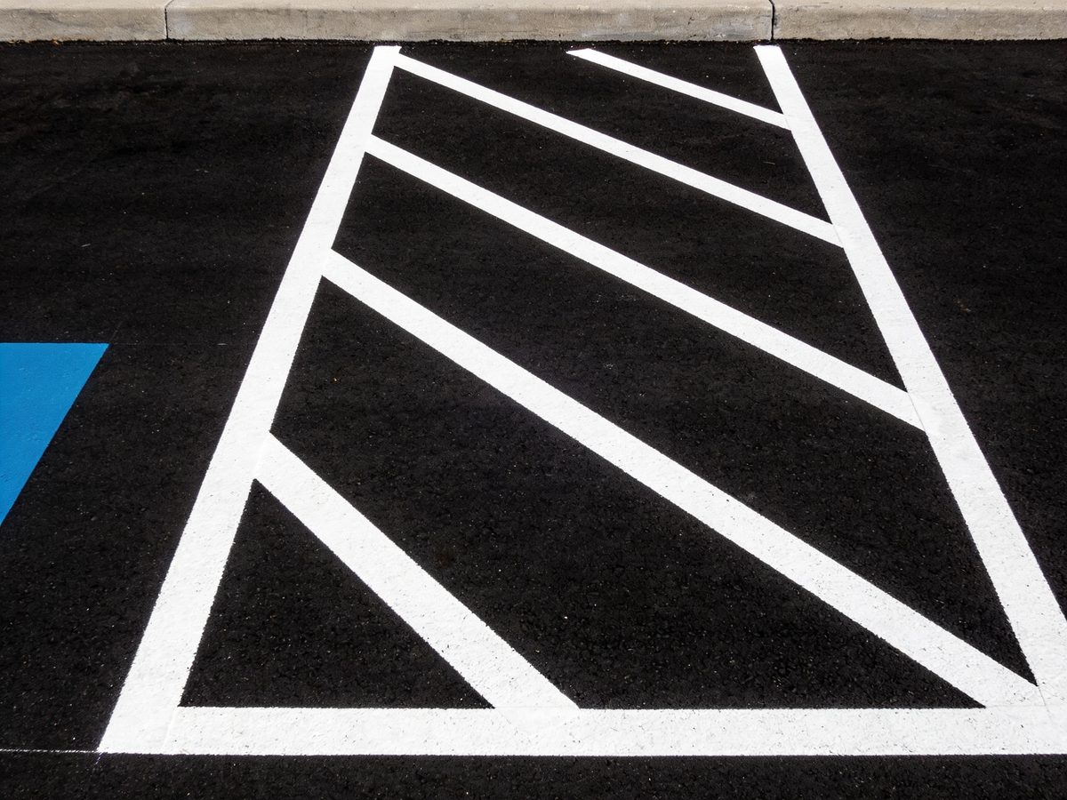 Freshly painted white parking stall lines on newly sealed black asphalt